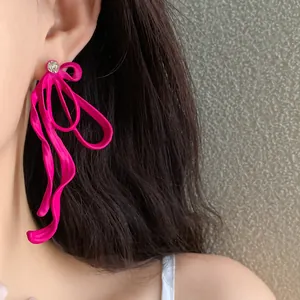 Close-up detail of vibrant magenta bow-shaped earrings with rhinestone accent on a model's ear