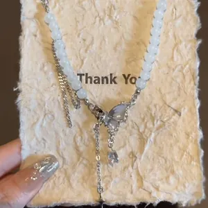 Collana di perle con ciondolo a farfalla e zircone su carta decorativa