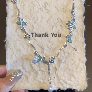 Elegante collana a farfalla d'argento con motivi azzurri e dettagli di perle a goccia