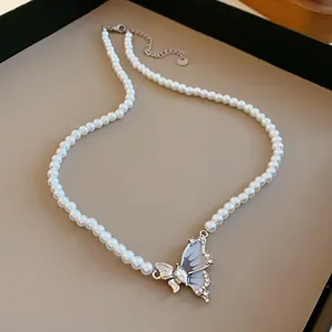 Primo piano di un ciondolo a farfalla in zircone su una collana di perle bianche