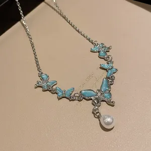 Dettaglio della collana a farfalla argentata con smalto blu e ciondolo di perla.