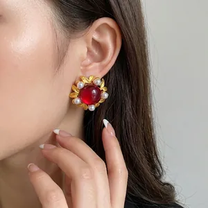 Vintage palace style flower stud earrings with red cabochon and pearls on model