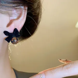 Dettaglio di eleganti orecchini a fiocco floccato nero con esclusiva perla ambrata