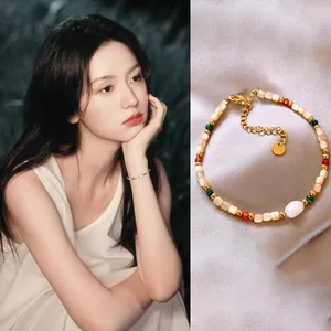 Close-up of an ethnic style beaded bracelet featuring 18K gold plating, pearls and shells.