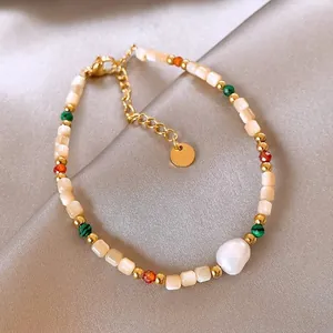 Close-up of bohemian shell and baroque pearl beaded bracelet with 18K gold plating