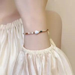 Close-up of beaded bracelet featuring shell heart and 18K gold plated accents