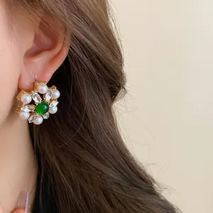 Detailed shot of vintage flower stud earring with green stone, crystals, and pearls