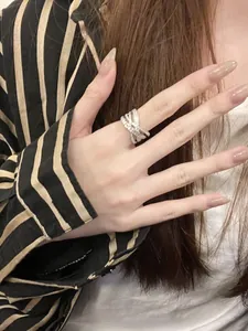 Close-up of sparkling zirconia criss-cross ring worn on index finger with striped sleeve