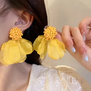 Detail view of vibrant yellow floral petal earrings with beaded cluster center.