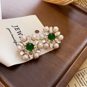 Detailed macro view of vintage flower earrings with green gemstone, white pearls and crystals