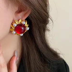Close-up of vintage red gemstone flower stud earrings with pearls on a model's ear.