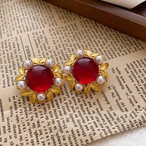 Vintage gold-tone leaf earrings with large red cabochon and faux pearl accents.