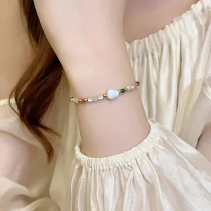 Close-up of elegant 18K gold-plated shell and pearl beaded bracelet on wrist