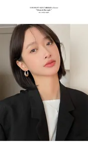 Model wearing minimalist silver-tone oval waterdrop hoop earrings with professional attire.