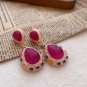 Macro view of vintage palace style teardrop earrings with magenta stones and blue crystals