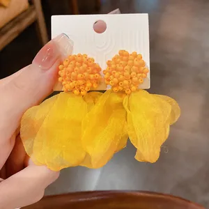 Detailed macro shot of yellow beaded cluster earrings with soft layered fabric petals.