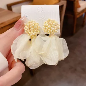 Close-up of elegant cream bead cluster and fabric petal earrings held on a card.