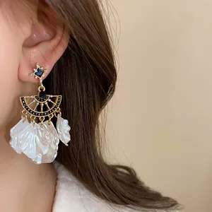 Detailed view of vintage court style blue rhinestone earrings with white shell petals