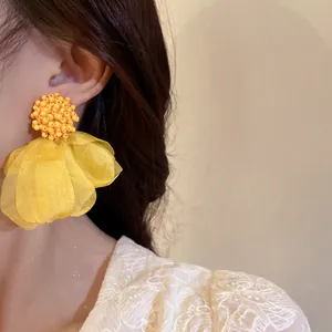 Detail of elegant yellow cluster petal earrings with silver needles on a model's ear