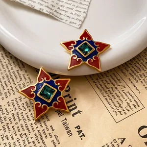 Detailed macro view of vintage star earrings with red and blue enamel and green crystal