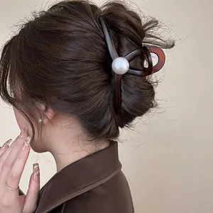 Détail d'une pince à cheveux géométrique marron avec une grande perle sur un mannequin