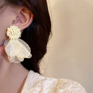 Close-up detail of elegant cream beaded cluster with translucent organza petal drop earrings