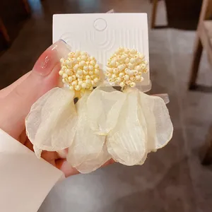 Detailed close-up of pale yellow beaded floral petal earrings with delicate fabric texture