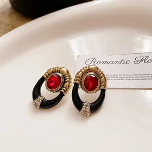 Detail shot of vintage red gemstone earrings with gold accents and black enamel finish.