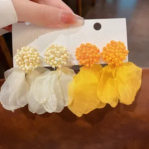 Close-up of clustered bead earrings with large fabric petal tassels in white and orange colors
