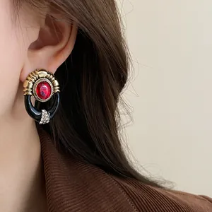 Detailed view of a vintage palace style gold earring with a red gem on an ear