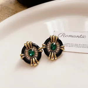 Close-up of vintage Baroque earrings with emerald green gemstones and gold accents