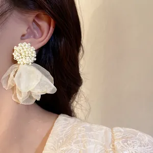 Close-up of elegant cluster bead earrings with light yellow organza petals on an ear