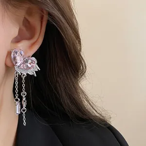 Close-up of vintage butterfly earrings with pink teardrop crystals and dangling chains.