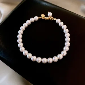 Élégant bracelet de perles vintage français avec fermoir doré sur boîte de présentation noire.
