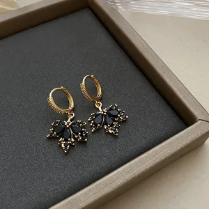 Macro detail of vintage gold hoop earrings with silver needles and black stone leaf pendants