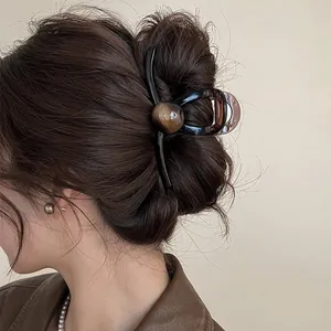Pince à cheveux géométrique vintage française marron café sur une coiffure en chignon.