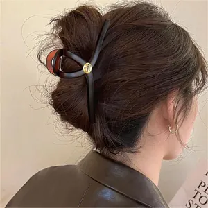 Détail d'une pince à cheveux géométrique marron de style français sur cheveux bruns