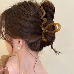 Détail d'une pince à cheveux ondulée marron portée dans un chignon classique.