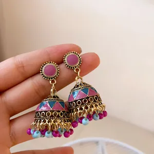 Close-up detail of retro Jhumka bell earrings featuring pink and teal enamel geometric patterns
