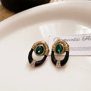 Detail view of vintage palace style earrings with emerald green stone and enamel
