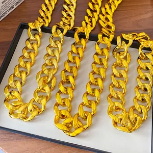 Close-up of chunky gold-colored acrylic curb chain necklaces in a minimalist tray.