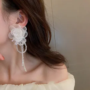 Close-up of elegant white mesh flower earring with crystal beaded tassel detail.