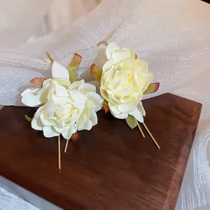Macro view of elegant cream fabric flower earrings with gold-toned metal stems