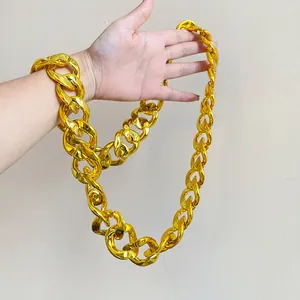 Close-up of a glossy gold acrylic chunky chain necklace held on a hand for scale