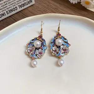Close-up of ethnic style enamel flower earrings with pearl dangles and pink rhinestones