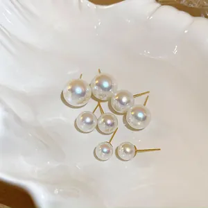 Dettaglio macro di eleganti orecchini con perle iridescenti in un piatto ceramico a conchiglia