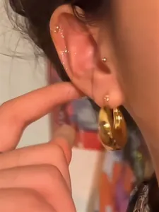 Close-up detail view showing the golden chunky hoop earring worn on a person's earlobe.