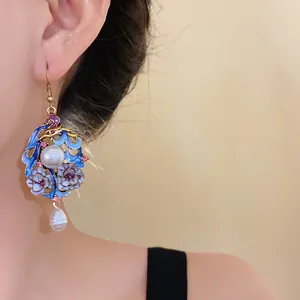 Detailed close-up of ethnic vintage palace style enamel flower and pearl dangle earrings.