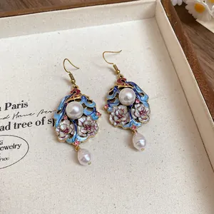 Close-up detail of elegant vintage enamel floral drop earrings with white pearl accents