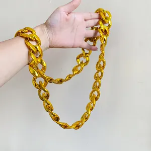 Close-up of chunky gold acrylic chain necklace held in hand showing size and scale detail